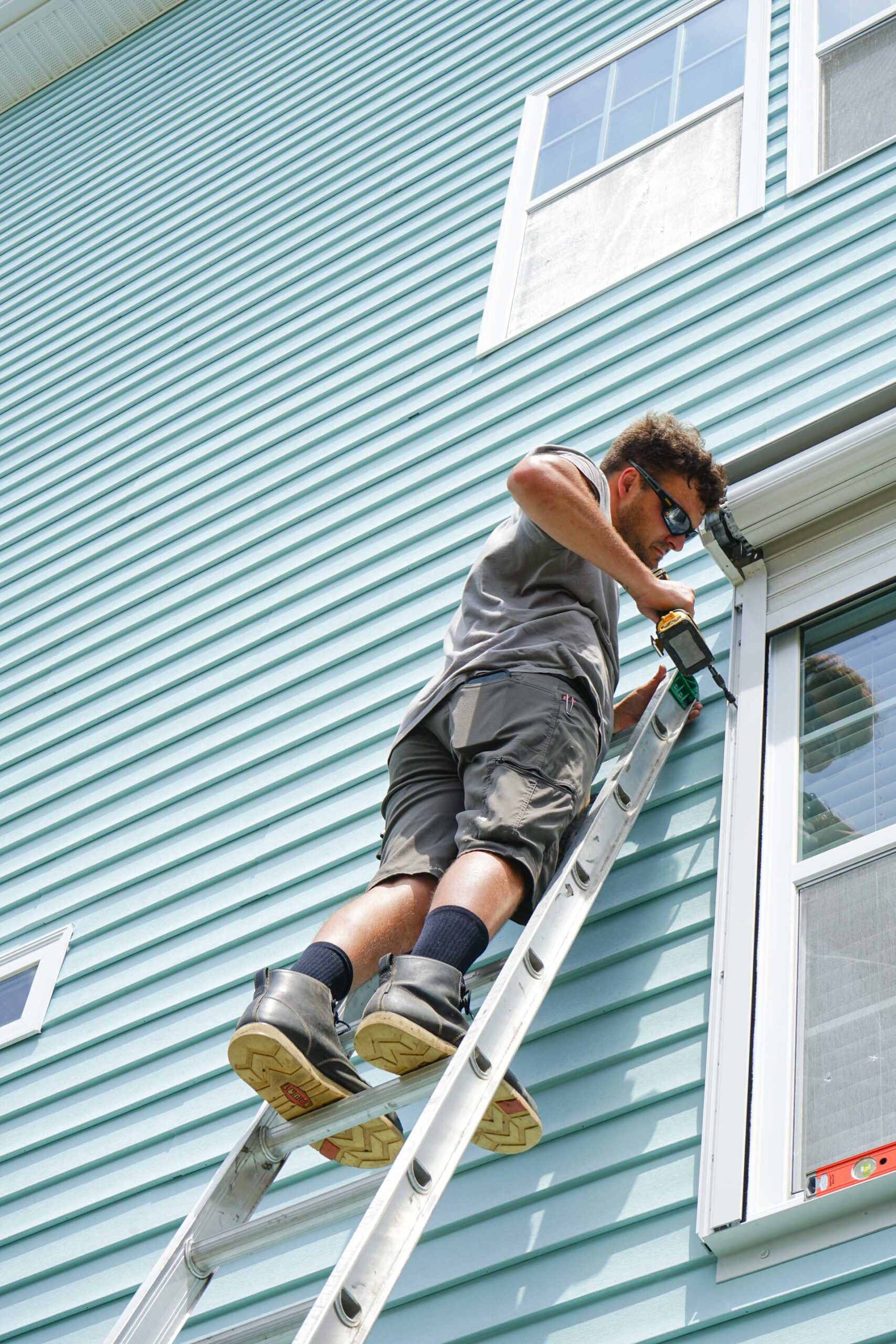 Gator Strong Services employee installing new roll-down shutters in Carolina Beach, NC.